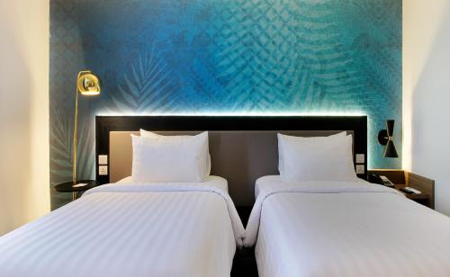 two beds sitting next to each other in a room at Swiss-Belinn Airport Surabaya in Sidoarjo