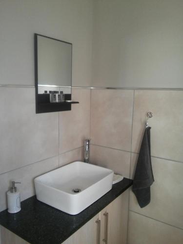 a bathroom with a white sink and a mirror at Marina Martinique Selfcatering in Jeffreys Bay