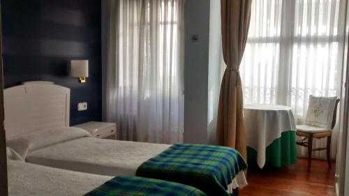 プレンツィアにあるCasa de marinos UribeKostaのベッドルーム1室(ベッド2台、テーブル、窓付)