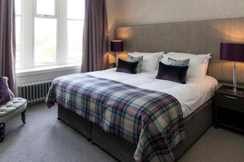 a bedroom with a large bed with purple pillows at The Dowans Hotel of Speyside in Aberlour