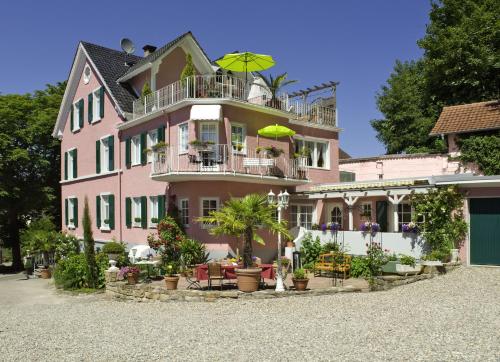 ein rosafarbenes Gebäude mit einem Balkon mit Sonnenschirm in der Unterkunft Boutiquehotel Villa Rosenhof in Badenweiler