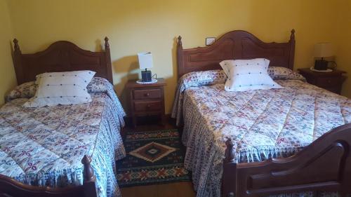 a bedroom with two beds and a lamp on a night stand at El Cotorollu in Onís