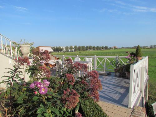 a porch with flowers and a white fence at Bed & Breakfast Het Zilte Zand - luxe ontbijt - gratis parking - Westende Middelkerke in Middelkerke