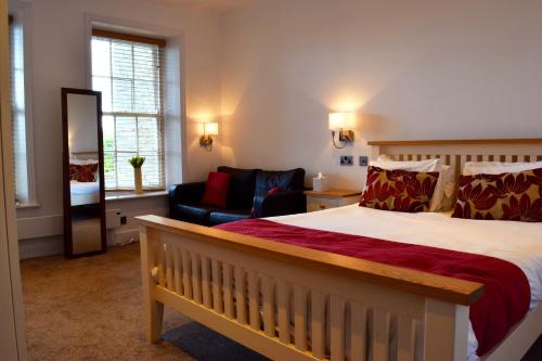 a bedroom with a bed and a couch and a chair at Healds Hall Hotel in Cleckheaton