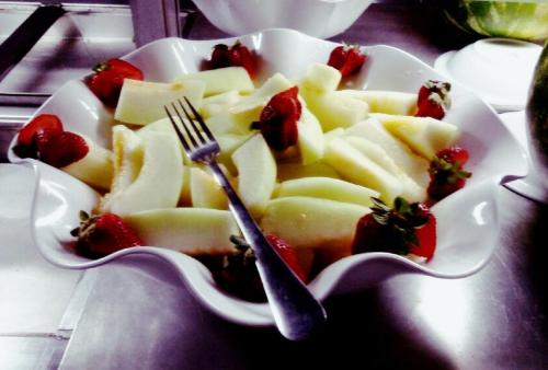 a white bowl of fruit with a fork and strawberries at Presidente Hotel in Poços de Caldas