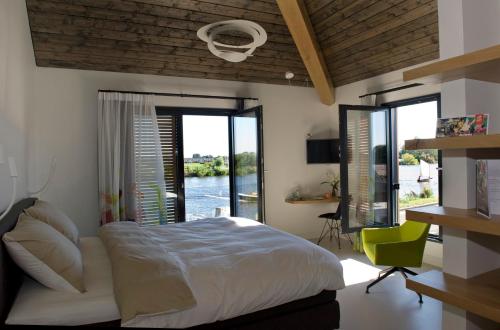 a bedroom with a bed and a view of a river at als het golft in Roelofarendsveen