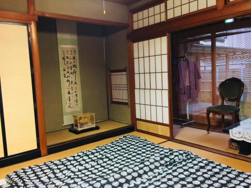 Hakusan Japanese-Style House في Hakusan: غرفة نوم بسرير وكرسي ونوافذ