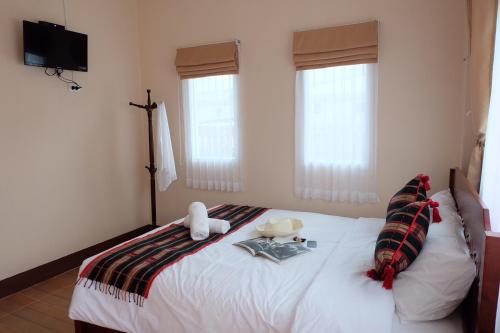 a bedroom with a large white bed with two windows at Latisha House in Chiang Rai