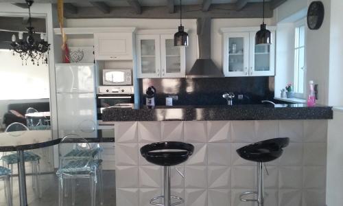 une cuisine avec des placards blancs et des tabourets noirs dans l'établissement Un Air De Famille, à Mauvezin