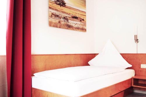 a bed in a room with a picture on the wall at Hotel Pension Kaempfelbach in Kämpfelbach