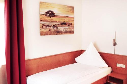 a bed in a room with a picture on the wall at Hotel Pension Kaempfelbach in Kämpfelbach