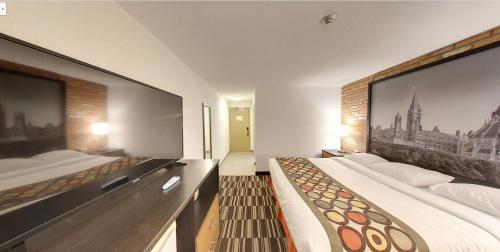 a bedroom with two beds and a large screen at Super 8 by Wyndham Sudbury ON in Sudbury