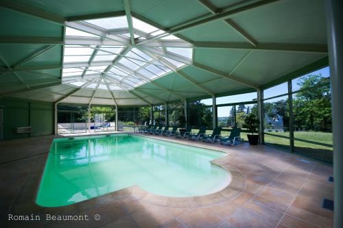 an indoor swimming pool with a glass ceiling at Le Domaine des Roches, Hotel & Spa in Briare
