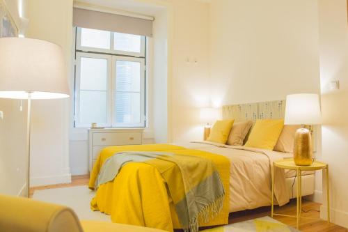 a bedroom with a bed with yellow sheets and a window at Rent4Rest - Lisbon Downtown Designer's Apartment in Lisbon