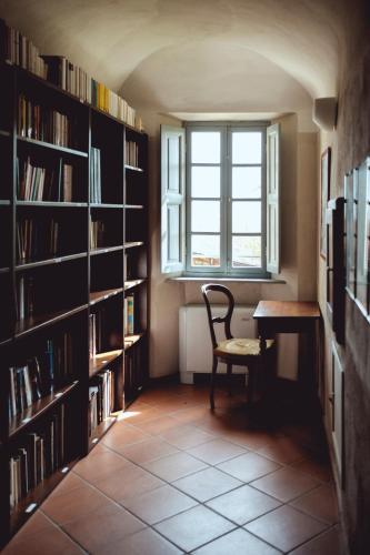a library with a chair and a desk and a window at Certosa 1515 in Avigliana
