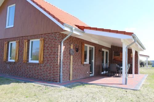 a brick house with a porch and a patio at Ferienhausgebiet Oberlangen in Oberlangen