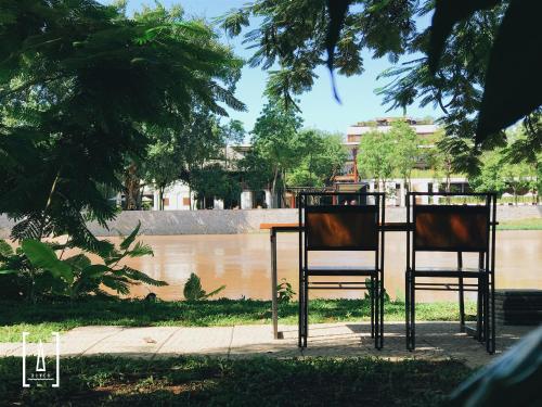 two chairs sitting at a table near a river at i-river chiangmai in Chiang Mai