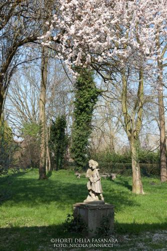 a statue in a park with a cherry tree at Horti Della Fasanara in Ferrara