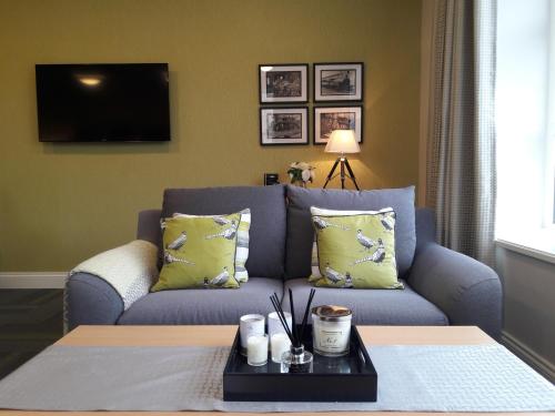 a living room with a blue couch with yellow pillows at The Sidings Inverurie in Inverurie