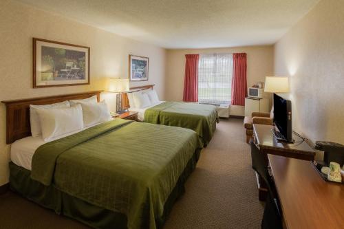 a hotel room with two beds and a television at Coshocton Village Inn & Suites in Coshocton