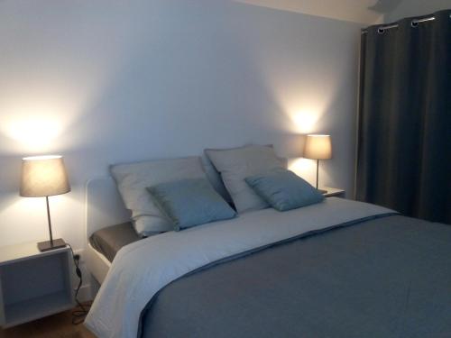 - une chambre avec un lit bleu et deux lampes dans l'établissement La Grange, à Foncquevillers