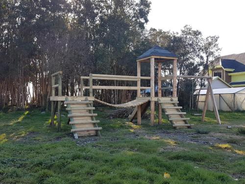 a wooden playground with a slide and a gazebo at Cabañas Torre Huillinco in Huillinco