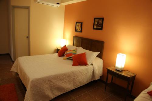 1 dormitorio con 1 cama con paredes de color naranja y 2 lámparas en Hotel Bulevar, en Paysandú