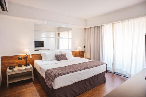a hotel room with a large bed and a television at Hotel Golden Park Campinas Cambuí By Nacional Inn in Campinas