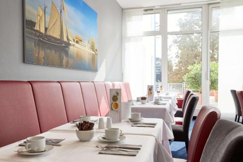 eine Reihe von Tischen in einem Restaurant mit rosa Stühlen in der Unterkunft Atlantic Hotel Vegesack in Bremen-Vegesack