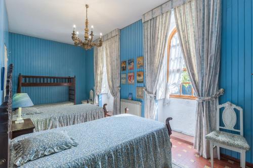 1 dormitorio azul con 2 camas y ventana en Casa de Fagilde, en Canedo
