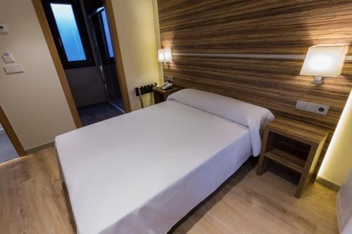 a bedroom with a white bed and a wooden wall at Hotel Novo Cándido in Ourense