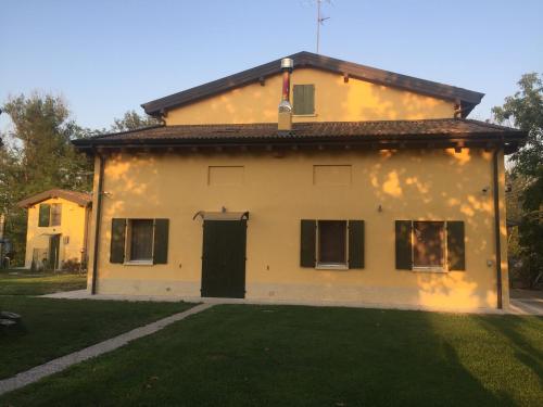 a large yellow house with a black door at B&B Nido Sui Laghi in San Donnino della Nizzola