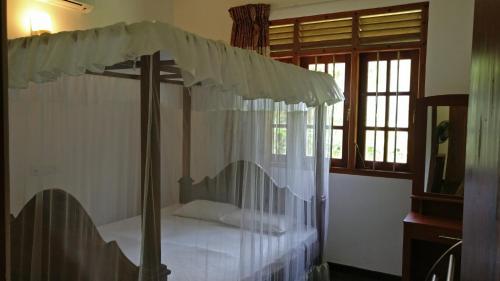 Schlafzimmer mit Himmelbett und weißen Vorhängen in der Unterkunft Bird Villa in Galle