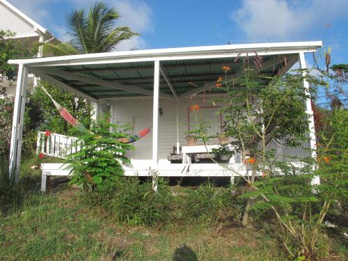 a white house with a porch with a bench at Green Roof Inn in Carriacou