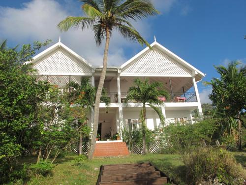 a house with a palm tree in front of it at Green Roof Inn in Carriacou