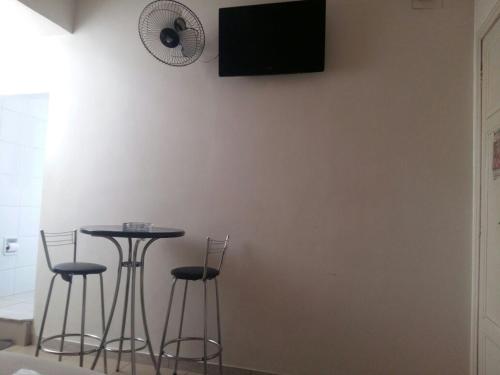 um quarto com uma mesa e bancos com uma televisão na parede em Motel Delamar (Adult Only) em Belo Horizonte