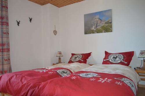 レ・コロンにある"Chalet le Dahlia - 4 Vallees"のベッドルーム1室(赤い枕のベッド2台付)