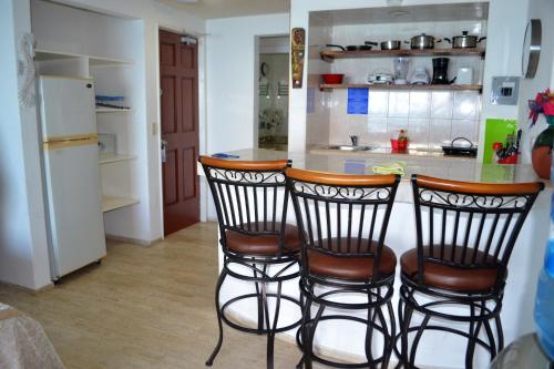 a kitchen with three bar stools and a refrigerator at Salvia Condominio in Cancún
