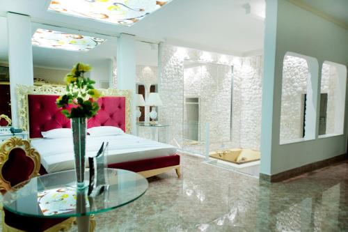 Eden Motel ( ADULT ONLY ) في تاوباتي: غرفة نوم بسرير وطاولة زجاجية وحوض استحمام