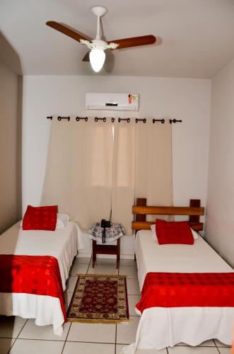 a room with two beds and a ceiling fan at Pousada Victor in Ribeirão Claro
