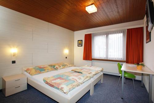 a bedroom with a bed and a desk and a window at Hotel Krone in Attinghausen