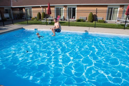 a man and a baby playing in a blue swimming pool at Super 8 by Wyndham Port Elgin in Port Elgin
