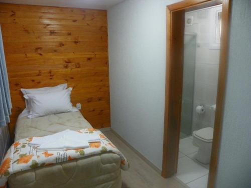 a small bedroom with a bed and a toilet at Casa Muller in Gramado