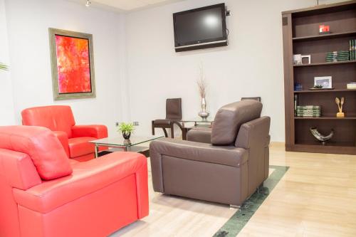 Una sala de estar con dos sillas y un televisor. en Hotel Carmen, en La Carlota