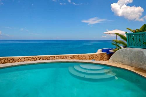 a swimming pool with a view of the ocean at The Caves in Negril