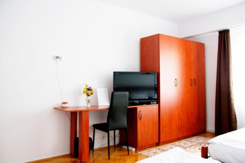 クルジュ・ナポカにあるAOL Cluj Apartのベッドルーム(デスク、テレビ付)、キャビネットが備わります。