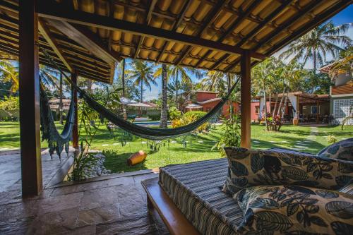 a hammock on the porch of a house with a yard at Pousada Recanto do Arraial in Arraial d'Ajuda
