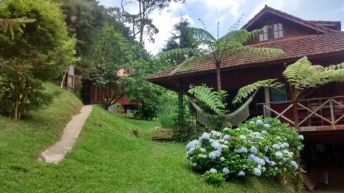 una casa con un arbusto de flores delante de ella en Pousada das Fadas, en Visconde De Maua