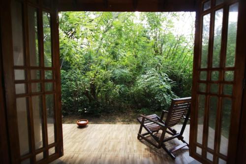 an open door to a porch with a rocking chair at Bissa Villa in Habarana