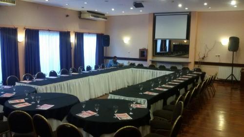 a conference room with tables and chairs and a man in a podium at Quintana Hotel in San Luis